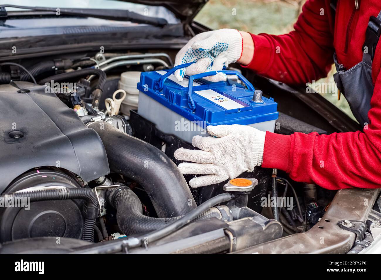 a car mechanic installs a battery in a car. Battery replacement and