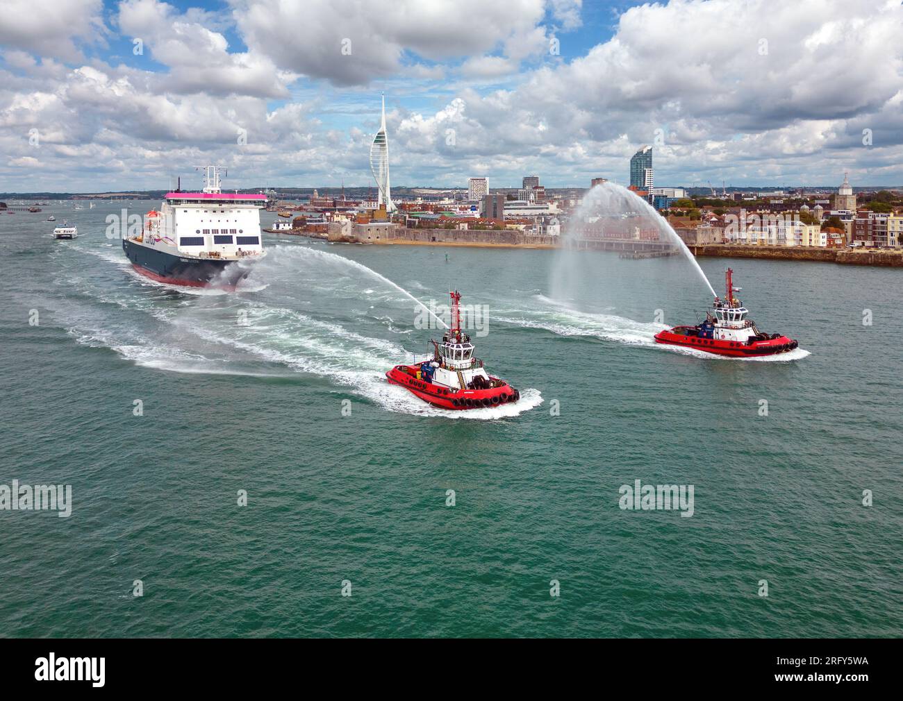 A tug escort with water salute for Condor Islander, a cross-Channel ROPAX ferry operated by Condor Ferries. Stock Photo