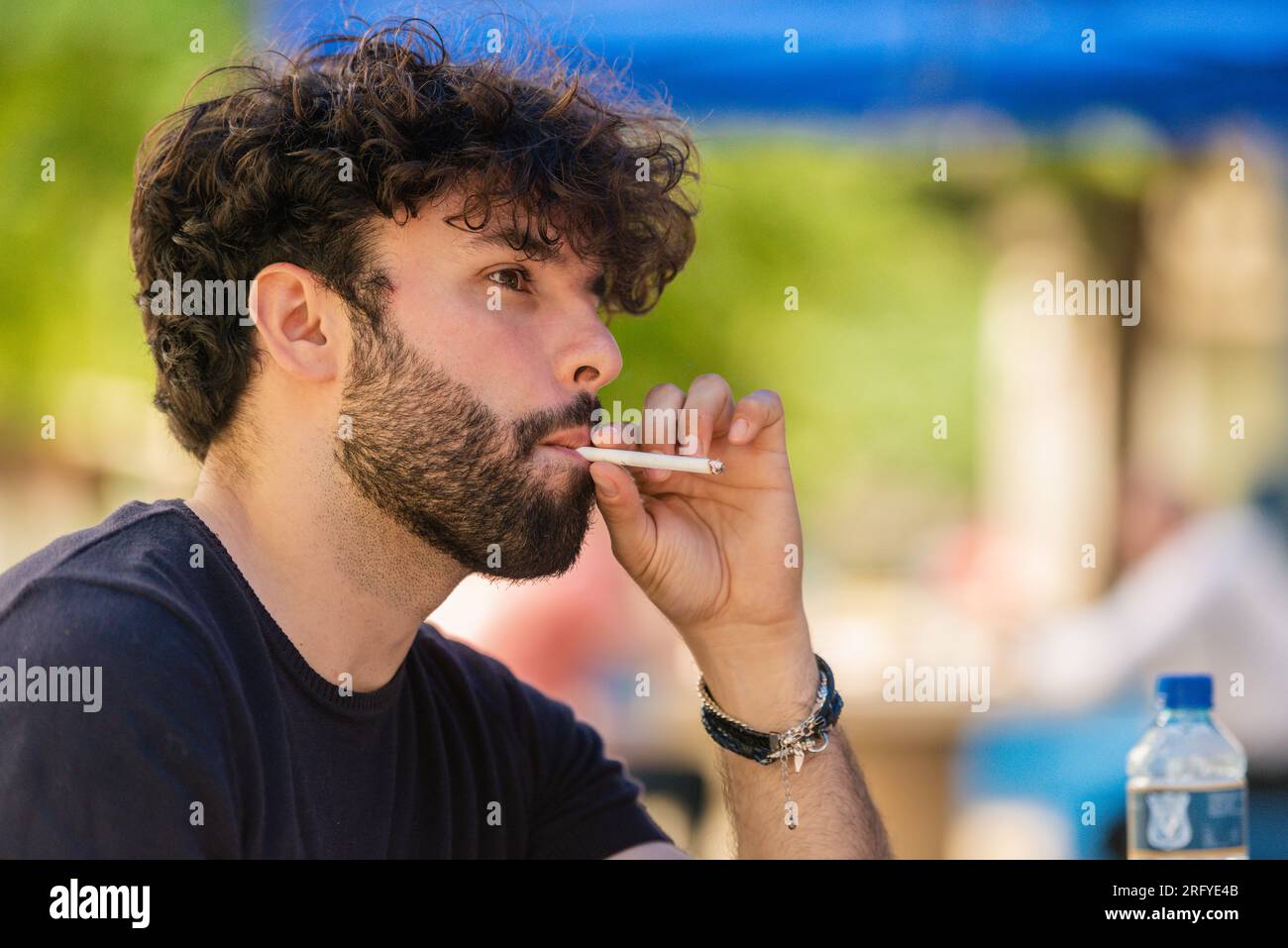 handsome man smoking cigarette Close-up portrait of a young and handsome man smoking a cigarette outside  Stock Photo