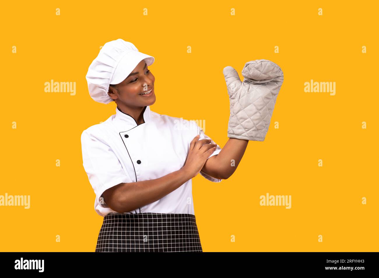 Happy Black Chef Woman Looking At Oven Mitt On Her Hand Stock Photo