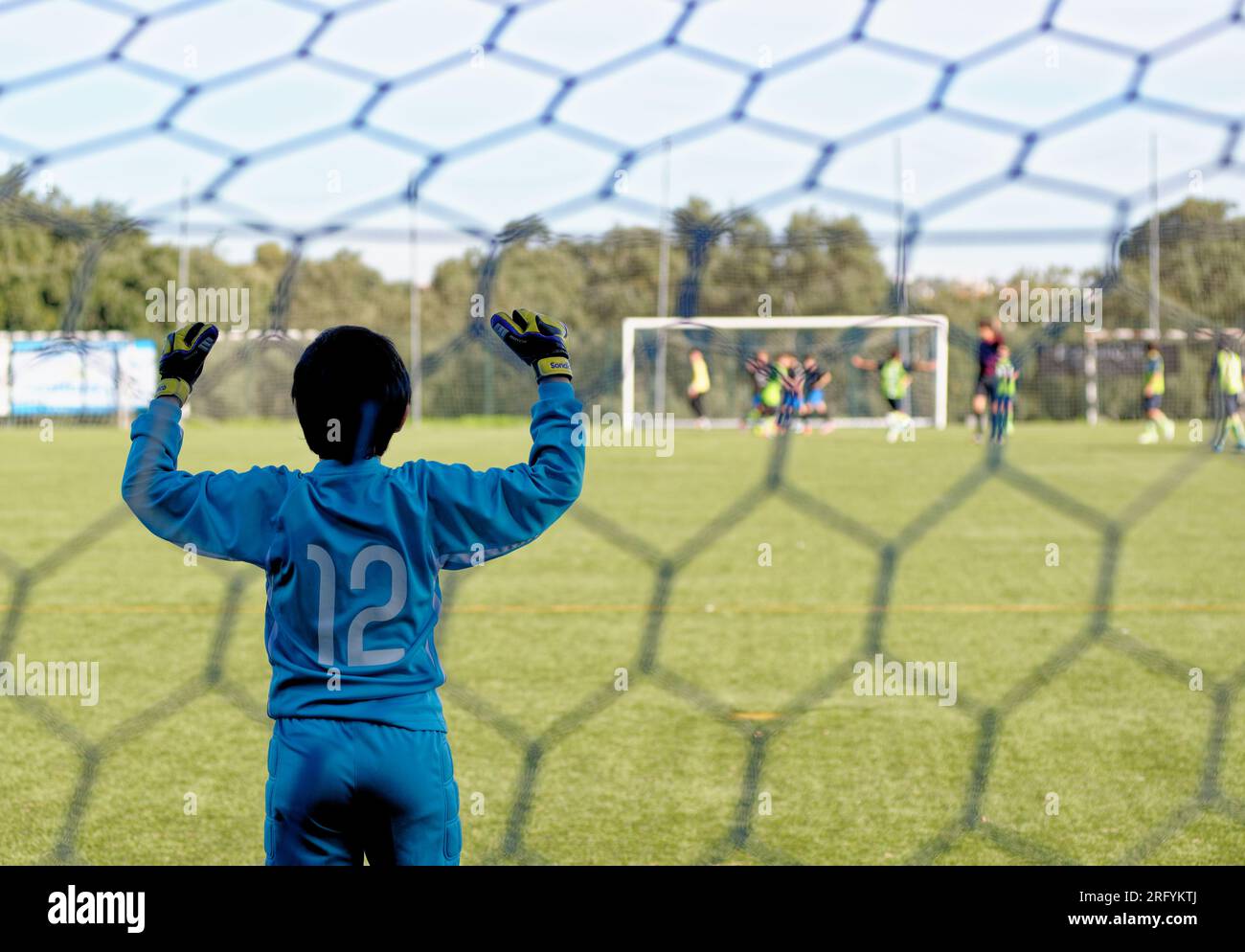 Young goalkeeper kid teenage boy playing football soccer game sports in