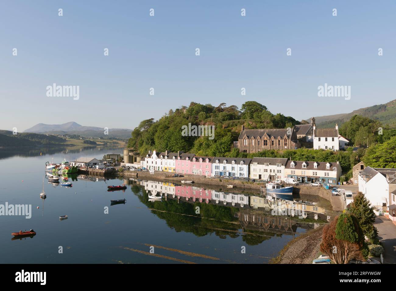 The Lump and the Brightly Coloured Buildings on Quay Street in Portree on the Isle of Skye Reflected in Loch Portree on a Calm Summer Morning Stock Photo