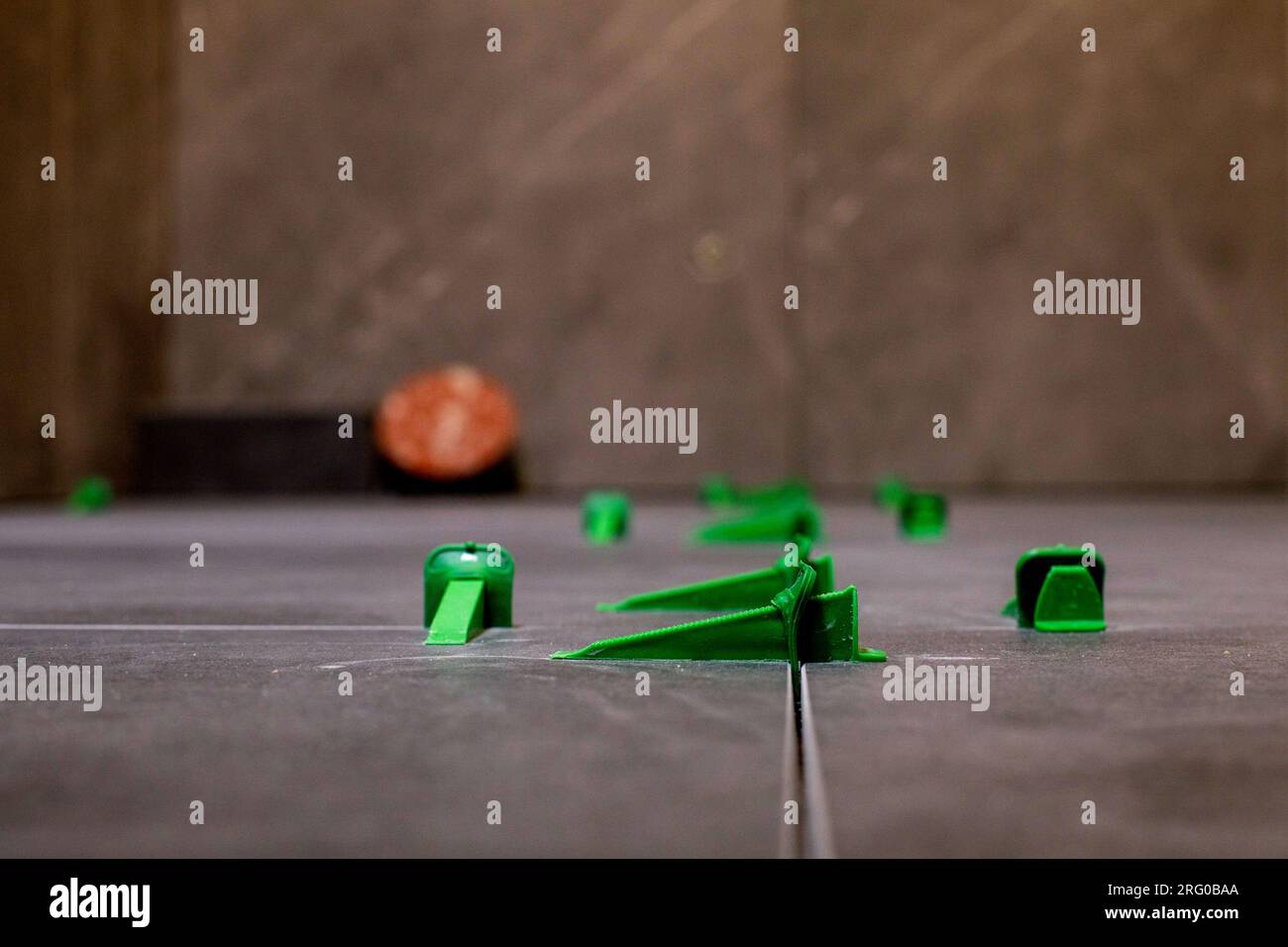 Tile levelling system, four plastic green clips with wedges. Close-up view, selective focus, blurred background. Stock Photo
