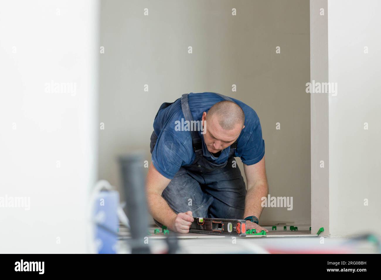 A male construction worker installs a large ceramic tile. Stock Photo
