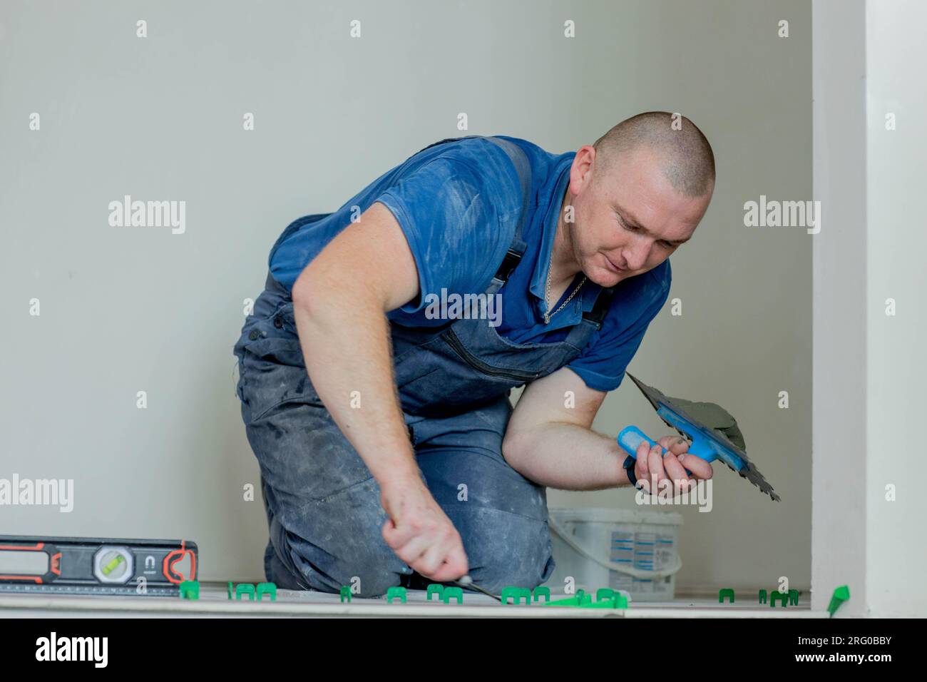 A male construction worker installs a large ceramic tile. Stock Photo