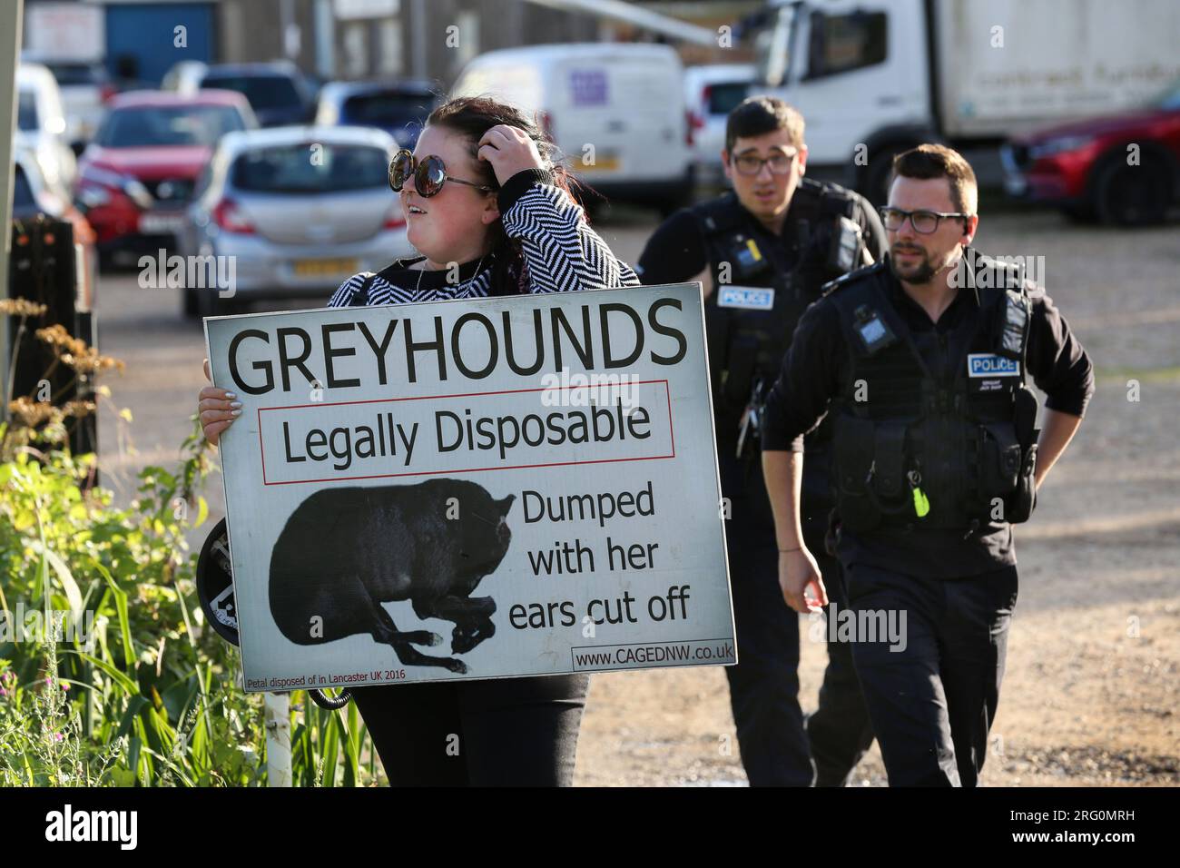 Henlow, UK. 06th Aug, 2023. A protester holding a placard reading 'Greyhounds Legally Disposable' outside the dog stadium is approached by police officers during the demonstration. Animal Rights activists protest outside Henlow dog racing track. They are aiming to highlight the cruelty associated with dog racing. In 2021 there were 4422 injuries and 120 deaths on registered greyhound race tracks in the UK. (Photo by Martin Pope/SOPA Images/Sipa USA) Credit: Sipa USA/Alamy Live News Stock Photo