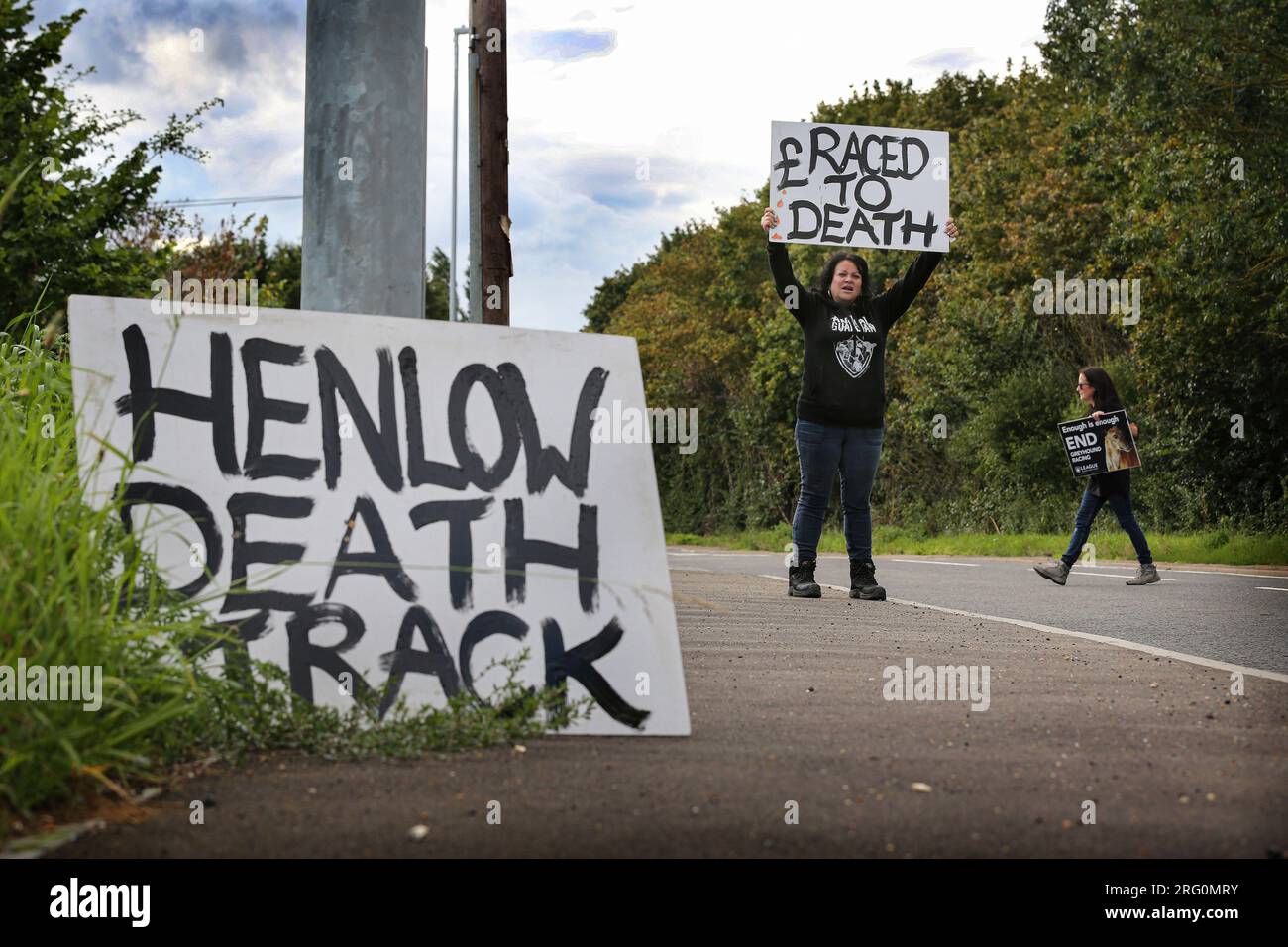 Henlow, UK. 06th Aug, 2023. Protesters lay a sign outside the dog stadium saying 'Henlow Death Track' while others encourage support from passing motorists by holding up roadside signs during the demonstration. Animal Rights activists protest outside Henlow dog racing track. They are aiming to highlight the cruelty associated with dog racing. In 2021 there were 4422 injuries and 120 deaths on registered greyhound race tracks in the UK. Credit: SOPA Images Limited/Alamy Live News Stock Photo