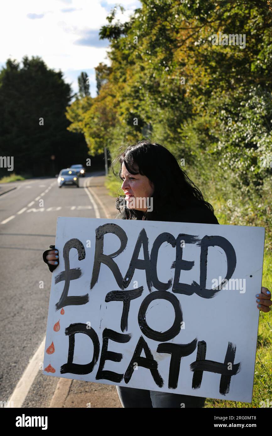 Henlow, UK. 06th Aug, 2023. A protester holds a placard saying '£ Raced to Death' at the roadside opposite the dog stadium during the demonstration. Animal Rights activists protest outside Henlow dog racing track. They are aiming to highlight the cruelty associated with dog racing. In 2021 there were 4422 injuries and 120 deaths on registered greyhound race tracks in the UK. Credit: SOPA Images Limited/Alamy Live News Stock Photo