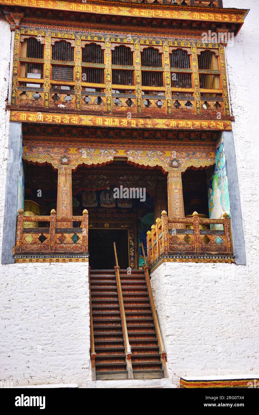 Steep stairs lead to the entry on an upper level of a colorful wooden building within the walls of the historic Punakha Dzong in the Kingdom of Bhutan Stock Photo