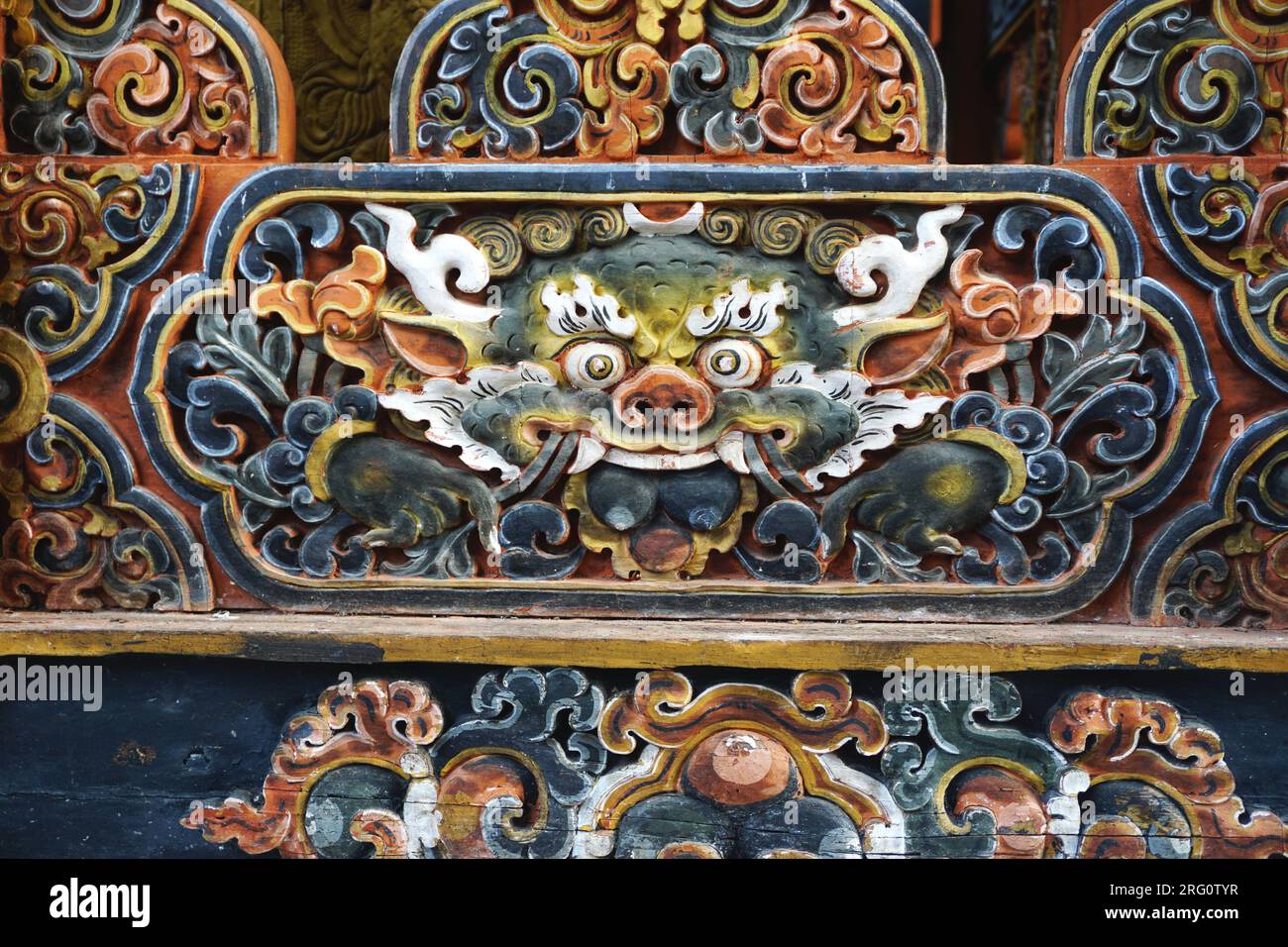 Detail of fierce carved and painted wooden dragon face cartouche at Punakha Dzong in the Kingdom of Bhutan. The dragon, or druk, is Bhutan's protector Stock Photo