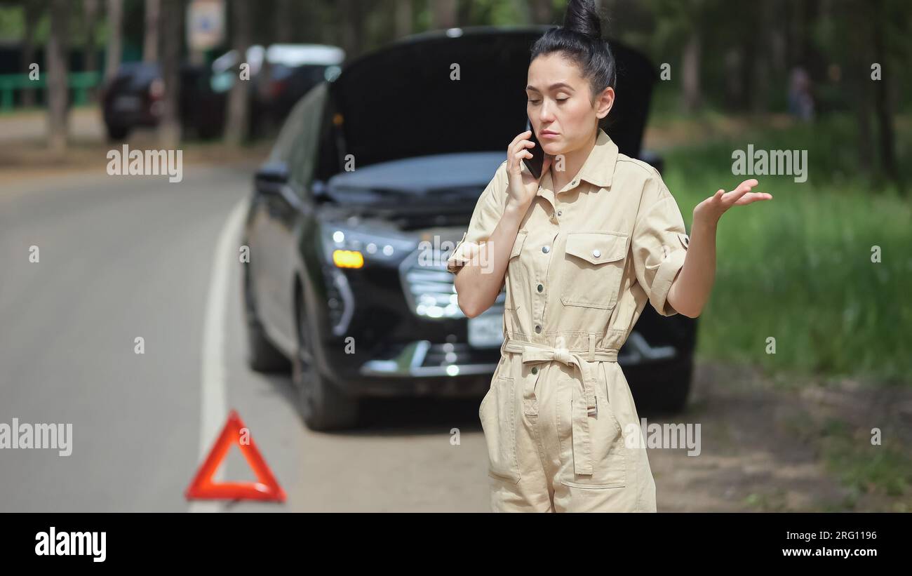 Woman calls car service to fix broken engine on roadside Stock Photo ...