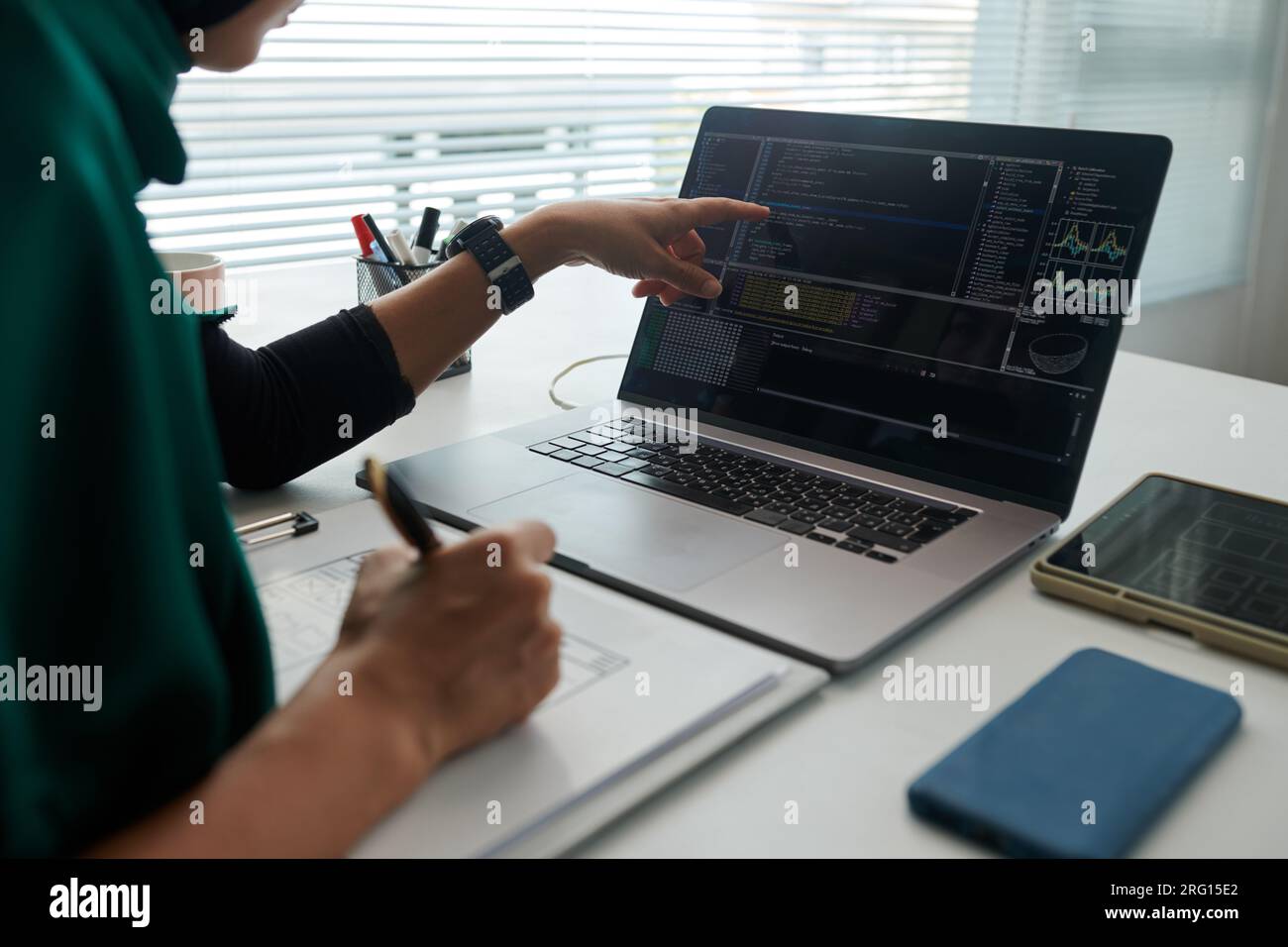 Muslim software developer pointing at laptop screen with programming code Stock Photo