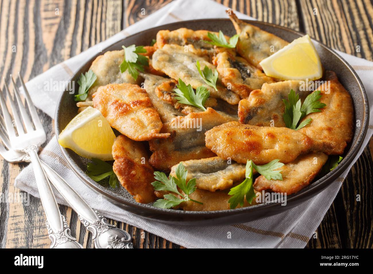 Plate of deep fried anchovies with lemon closeup on the table. Horizontal Stock Photo