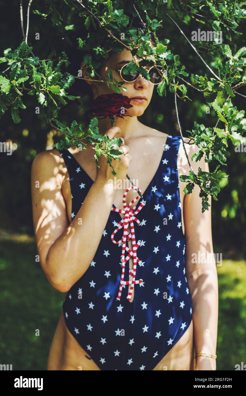 pretty young girl with red rose swimsuit among trees Stock Photo - Alamy