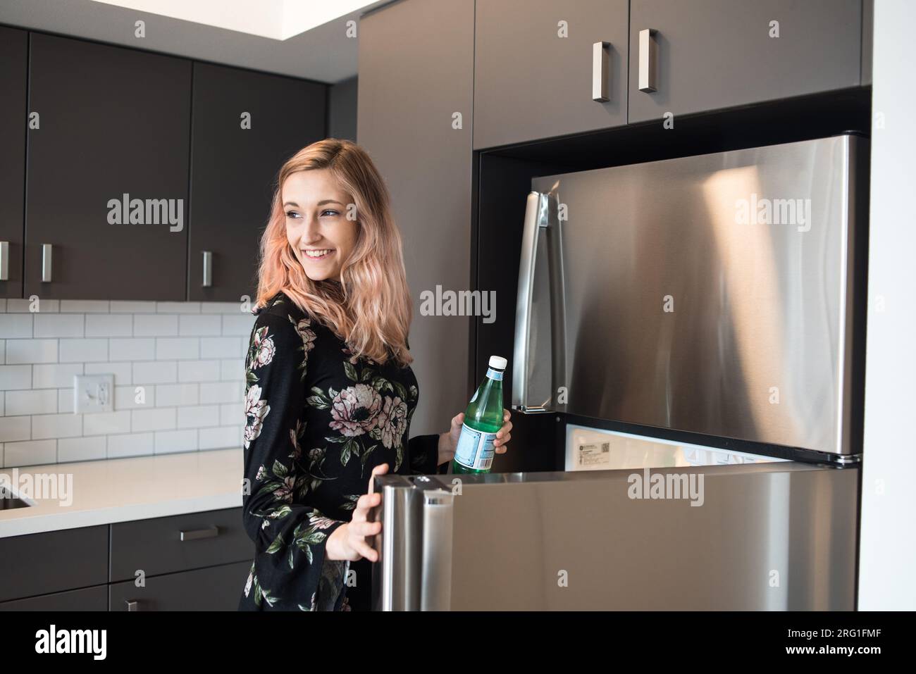 Woman grabbing drink from fridge and smiling Stock Photo Alamy
