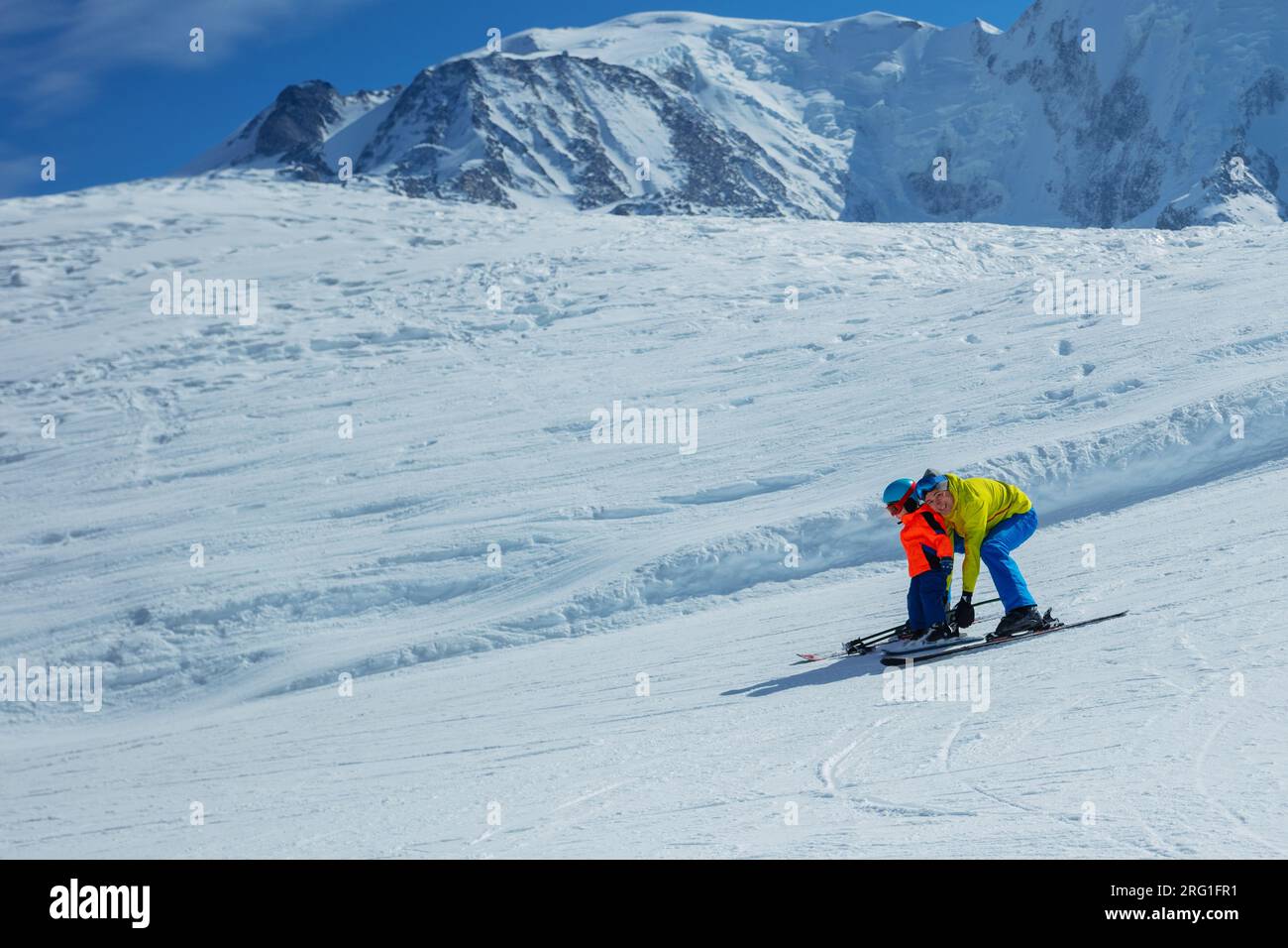 Father teach boy glide behind hold ski bindings with hands Stock Photo