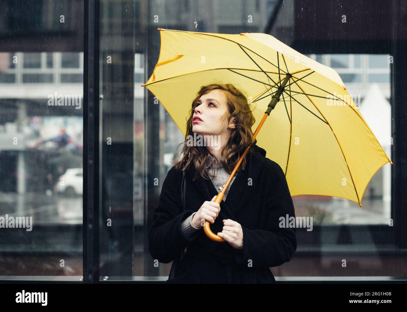 Young woman in the city holding yellow umbrella Stock Photo