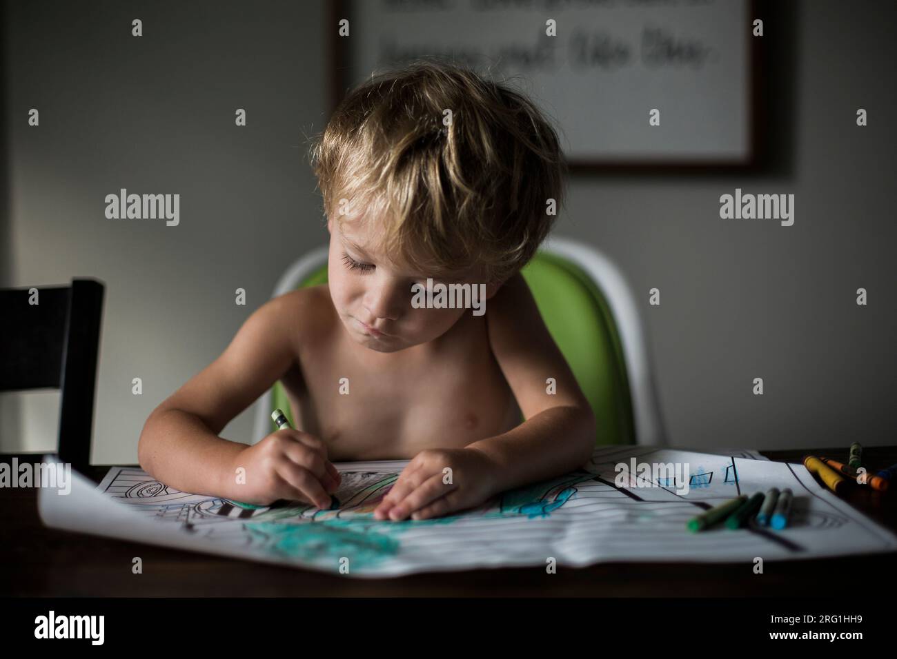 Young boy coloring at kitchen table Stock Photo