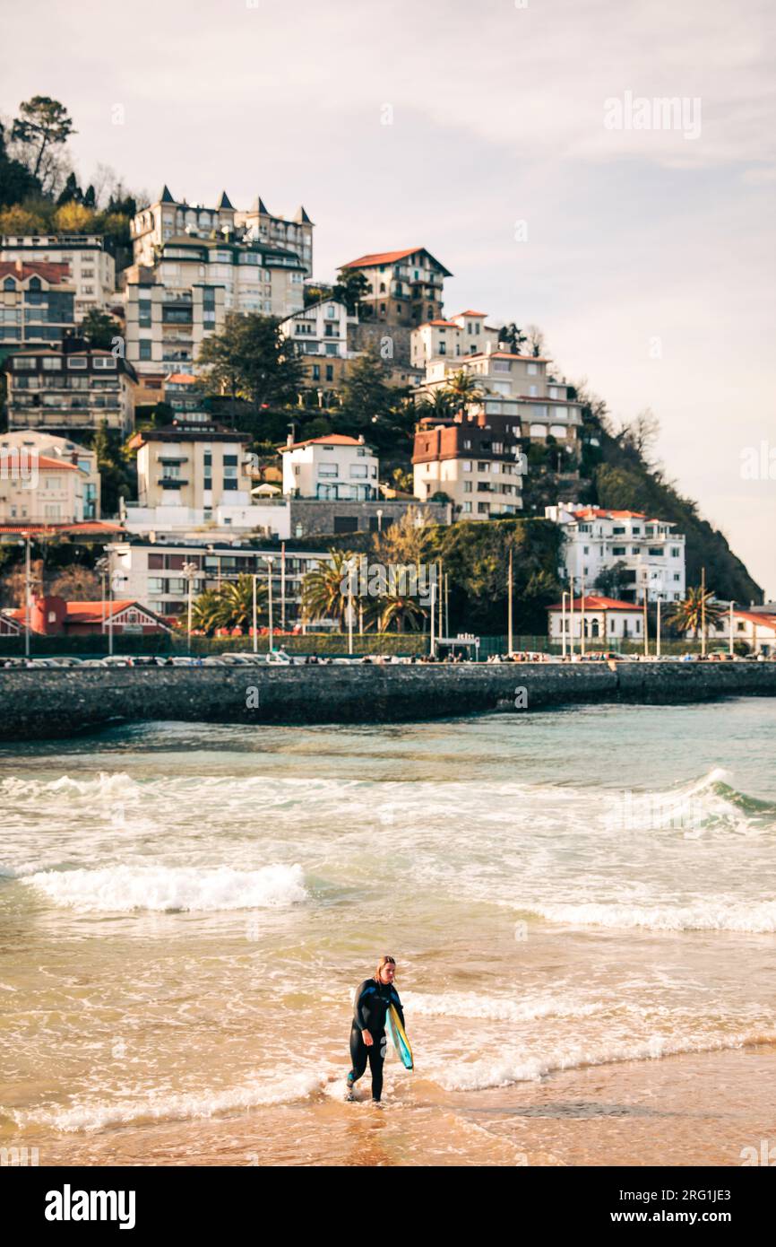 Surfer coming out of the sea water with houses in the background Stock Photo