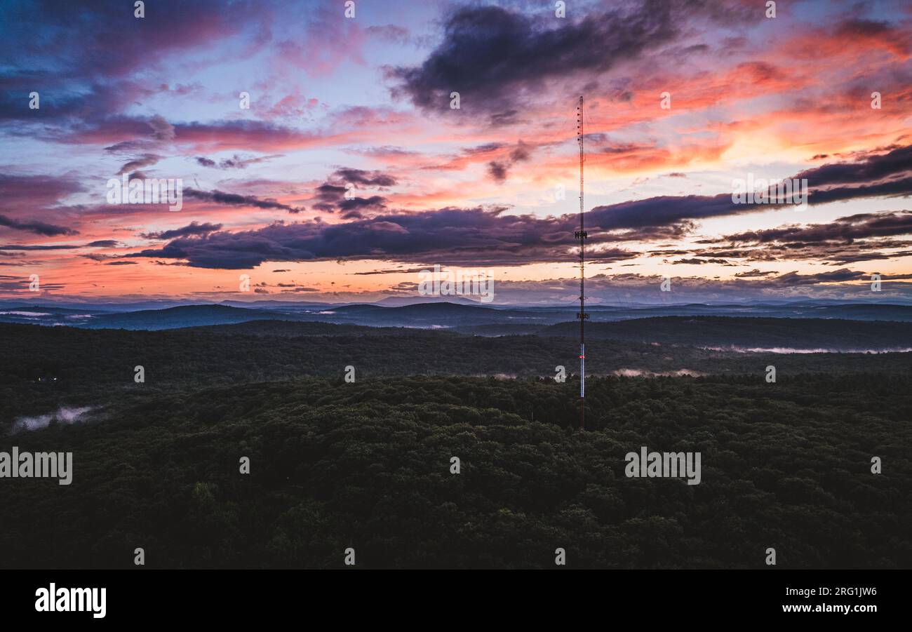 Radio communication cell tower at sunset in the woods of Maine Stock Photo
