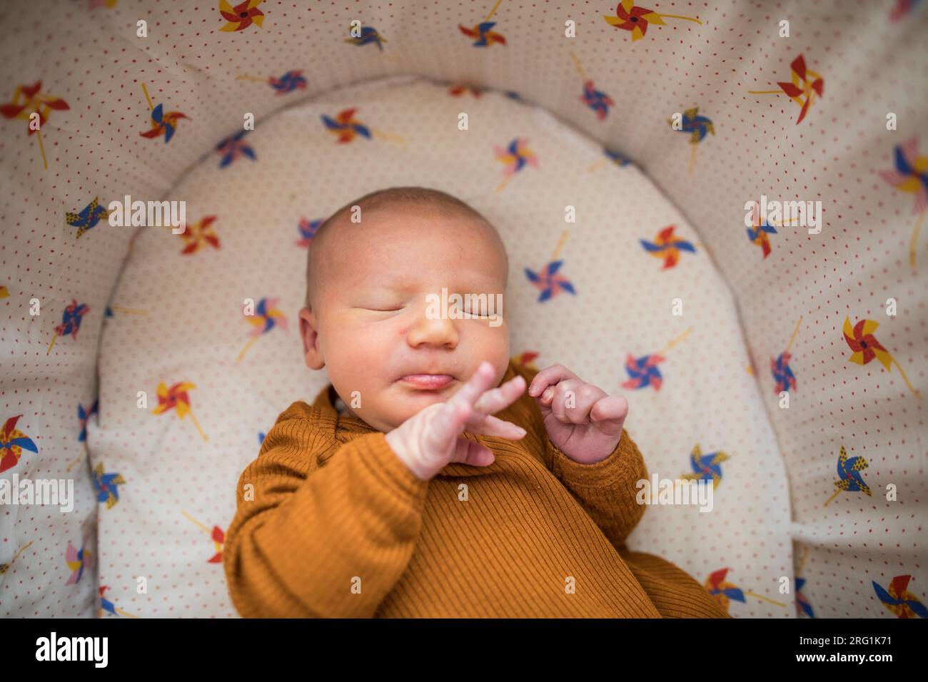Newborn baby holding out his little fingers while sleeping in bed Stock