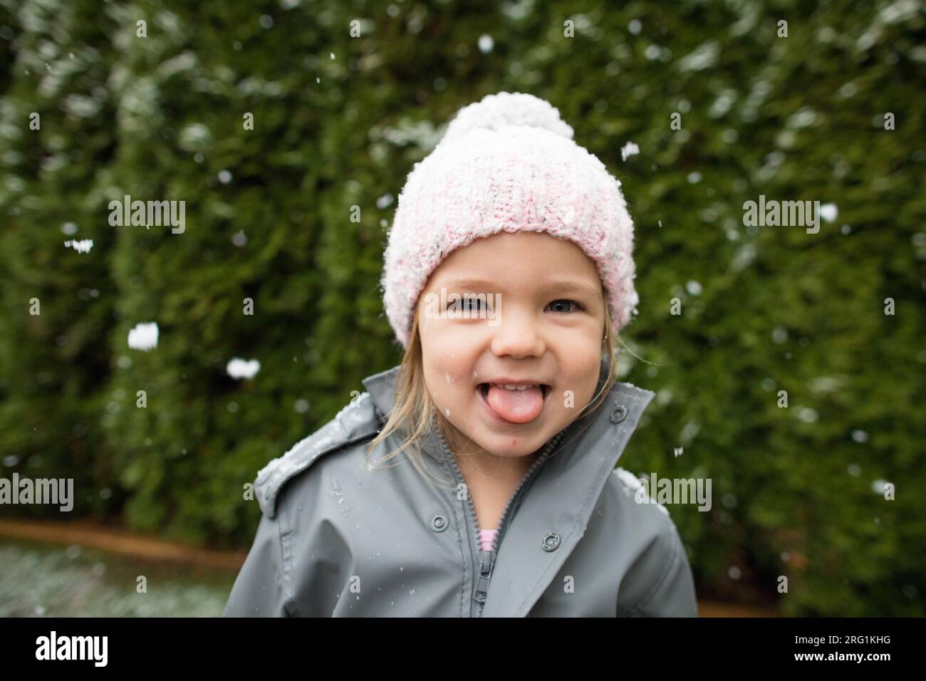 Cute young girl catches snowflakes with her tongue outside. Stock Photo