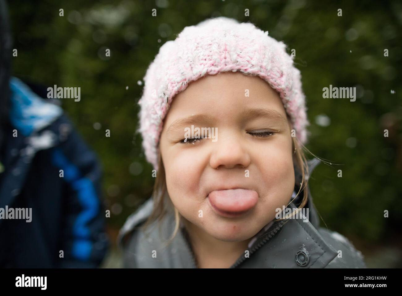 Young girl catches snowflakes with her tongue outside. Stock Photo