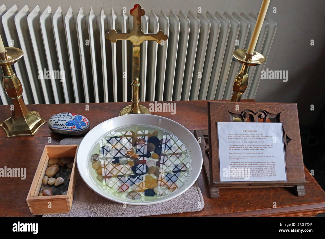 Pebble pool plate used for prayer and reflection displayed on a table inside a church in Heptonstall, West Yorkshire, England, alongside a cross Stock Photo