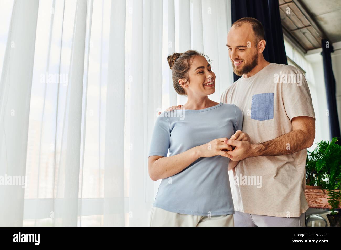 Positive couple in homewear holding hands while spending time together at home Stock Photo