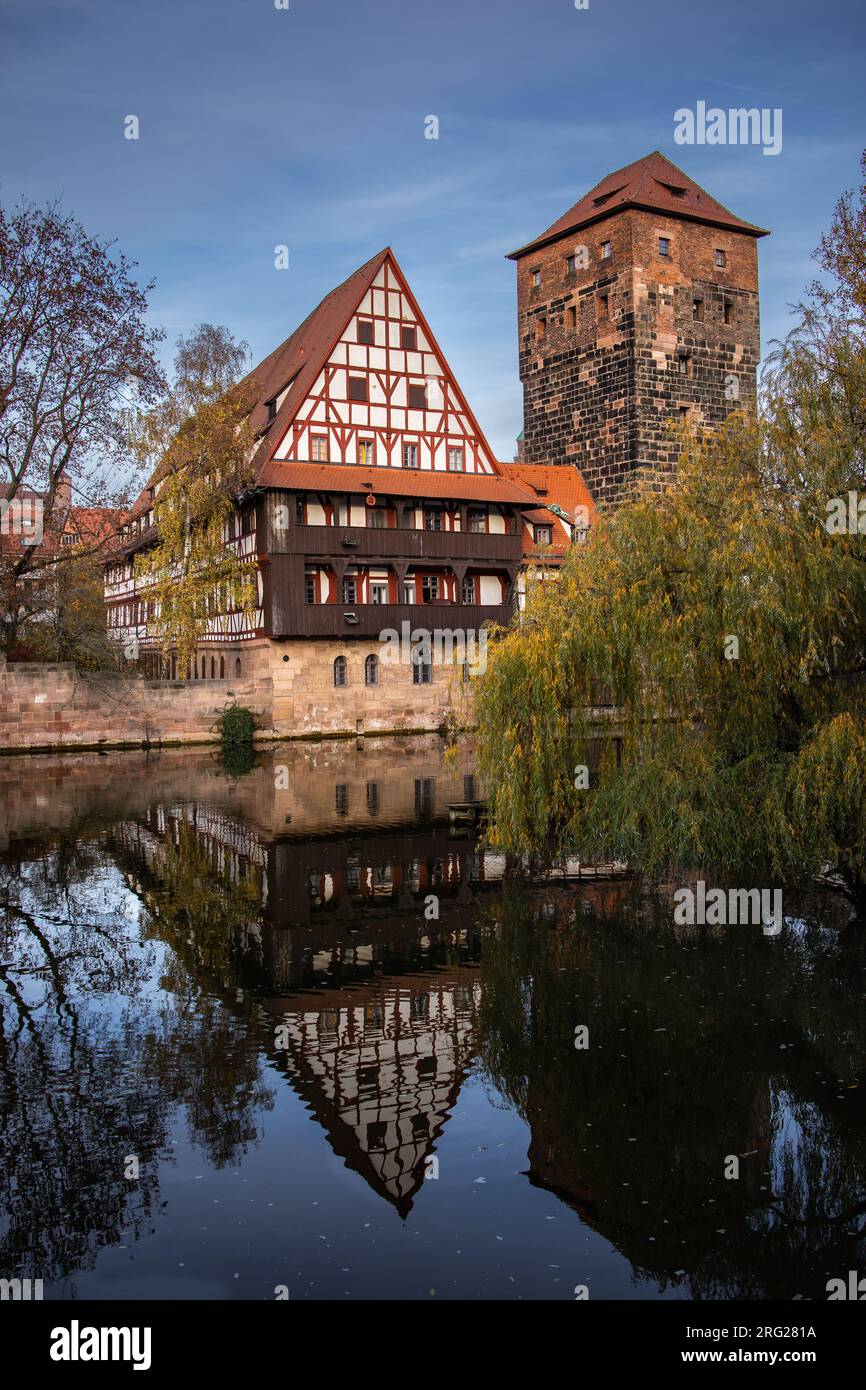 German Landmark in Nuremberg. Vertical Autumn Scenery of Water Tower with its Reflection in Pegnitz River. Stock Photo