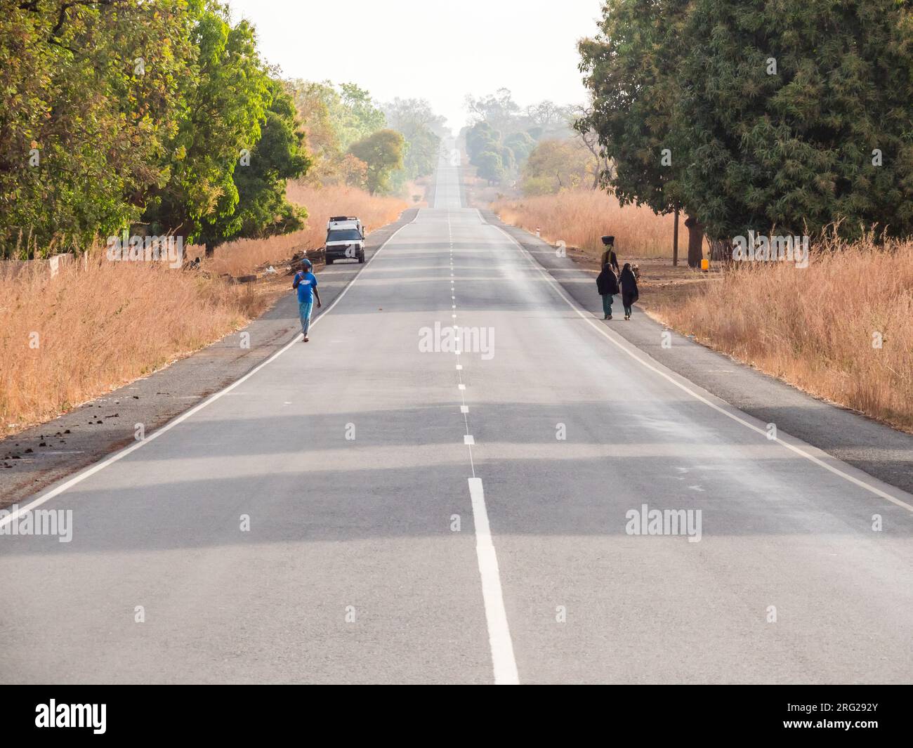 Typical landscape in the Gambia. People walking along the main road. Stock Photo