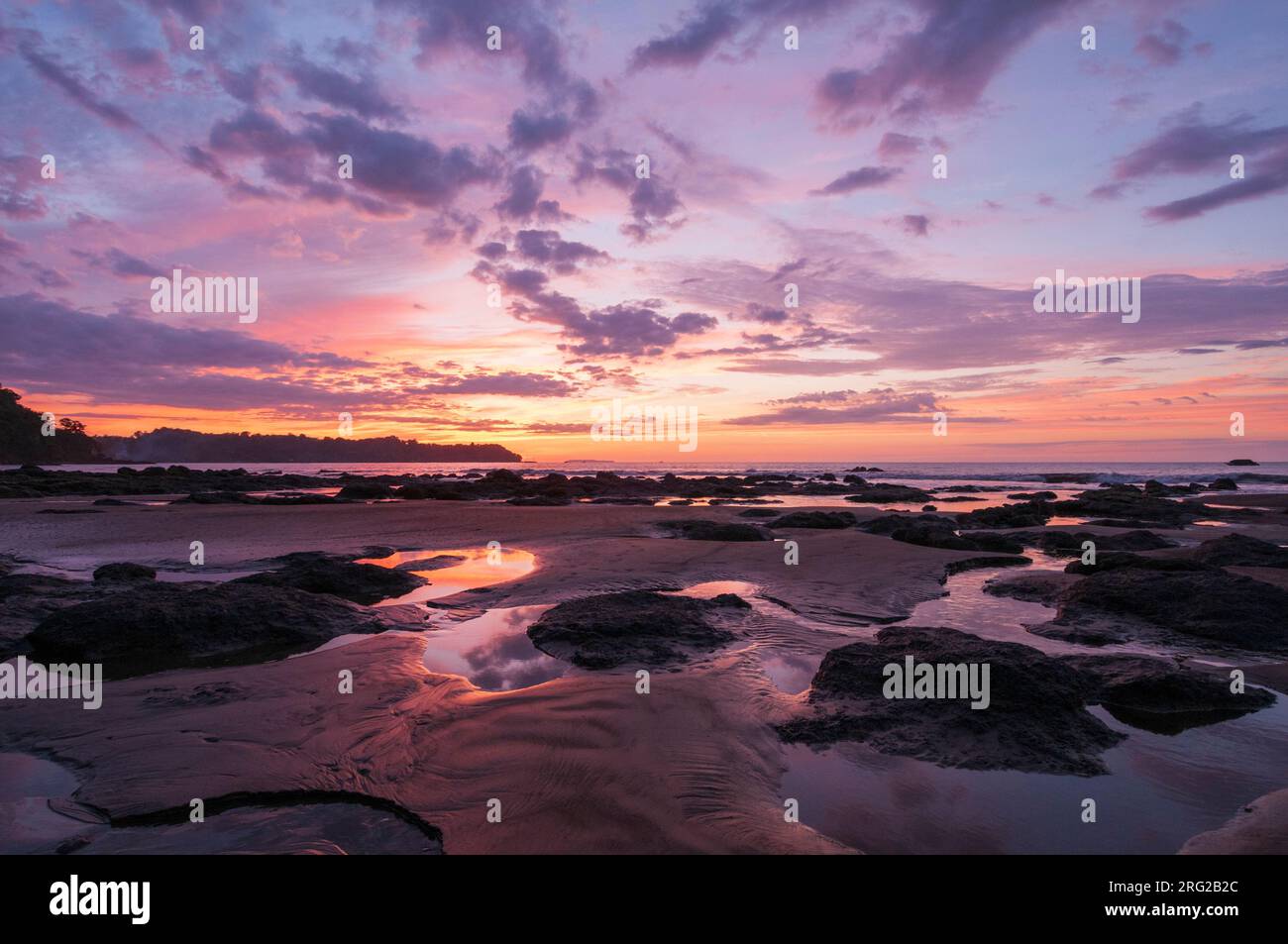 Puddles of water and piles of sand on a beach at sunset. Drake Bay, Osa Peninsula, Costa Rica. Stock Photo