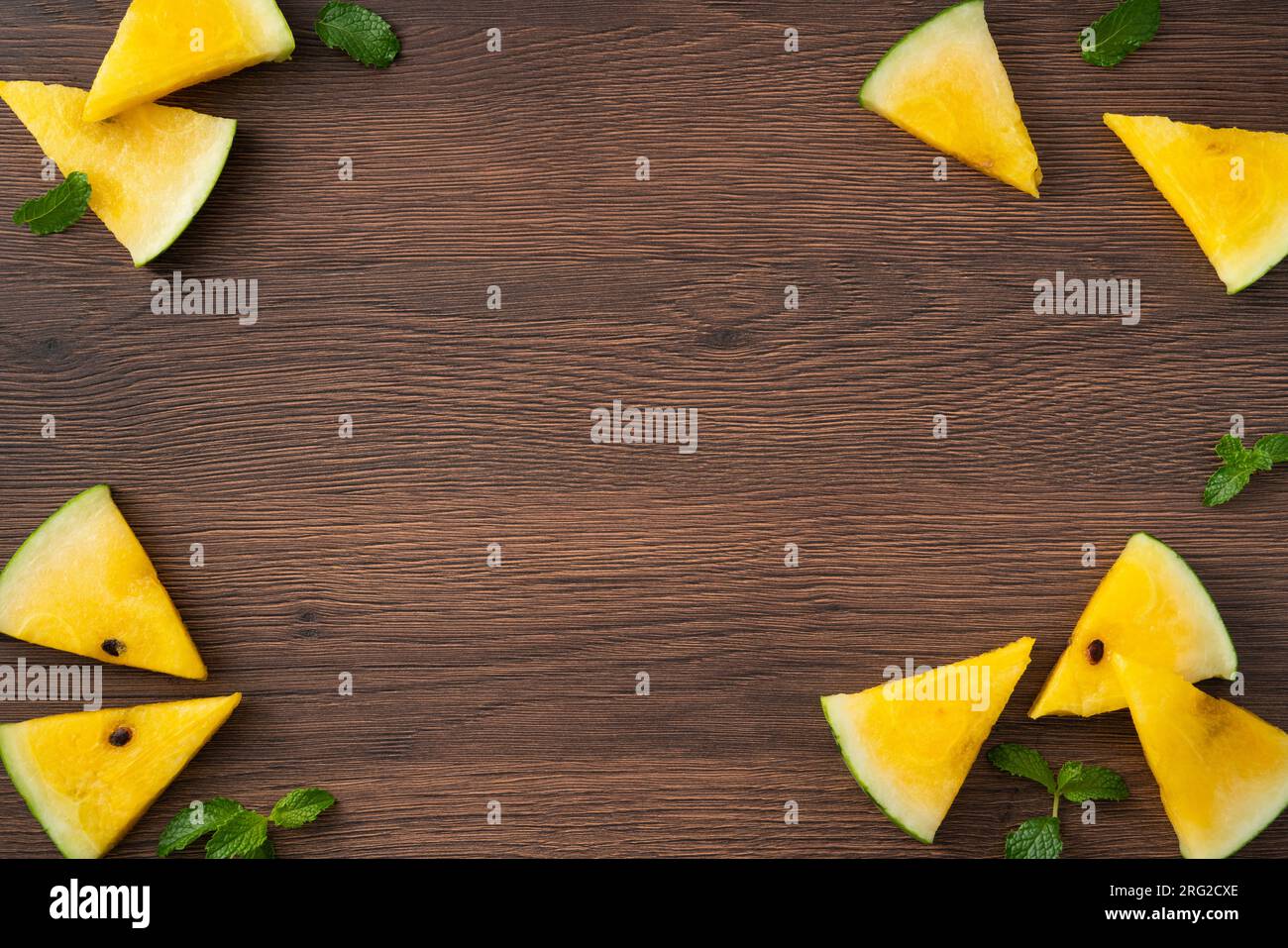 Sliced yellow golden watermelon pattern flat lay on wooden table background. Stock Photo