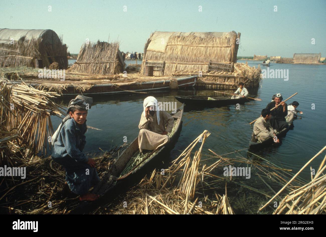Marsh Arabs Iraq. Marsh Arab man and woman in boats with children.Transport between islands known as dibin. Reed island houses. Rivers Tigris and Euphrates wetlands, Hammar marshes. Southern Iraq 1984  1980s HOMER SYKES Stock Photo