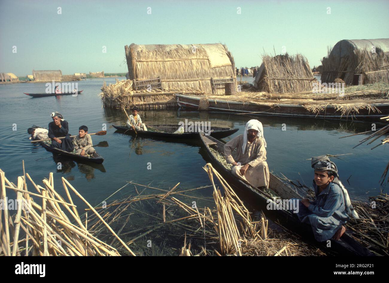 Marsh Arabs Iraq. Marsh Arab men in boats with children. Transport between islands known as dibin. Traditional reed island houses. Rivers Tigris and Euphrates wetlands, Hammar marshes. Southern Iraq 1980s 1984 HOMER SYKES Stock Photo
