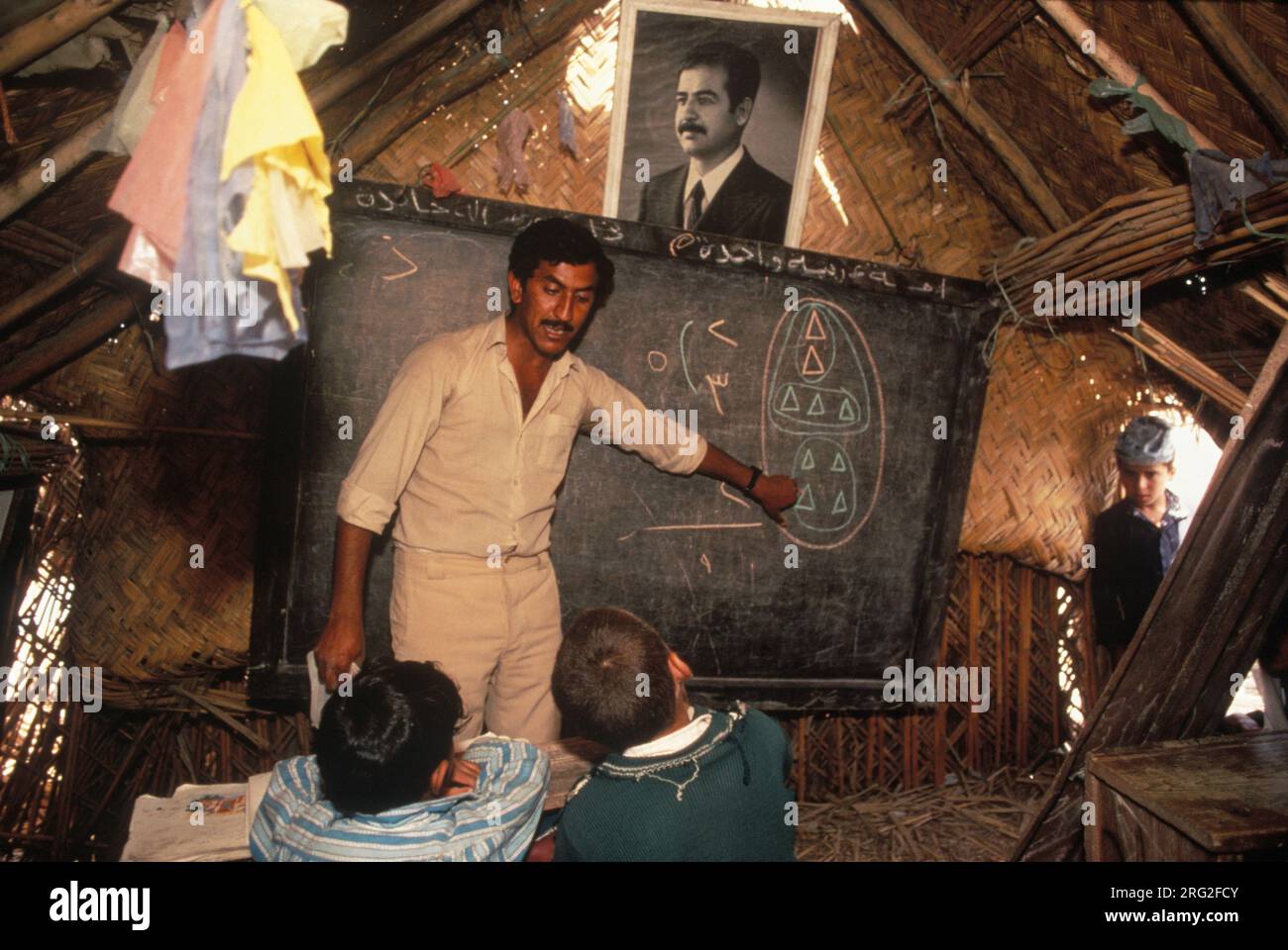 Marsh Arabs Southern Iraq.  Marsh Arab children in school a traditional reed constructed building. Portrait of Saddam Hussein hanging from wall. Hammar marshes Iraq 1984 1980s HOMER SYKES Stock Photo