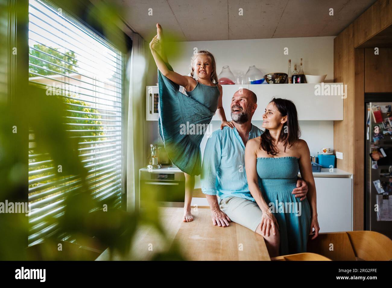 Little girl dancing on the kitchen countertop, while parents watching