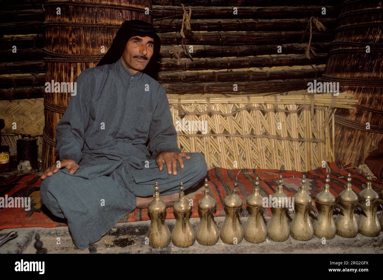 Marsh Arabs. Southern Iraq.  Marsh Arab man in communal village reed constructed building with coffee pots. Rivers Tigris and Euphrates wetlands, Hammar marshes. Southern Iraq 1980s 1984 HOMER SYKES Stock Photo