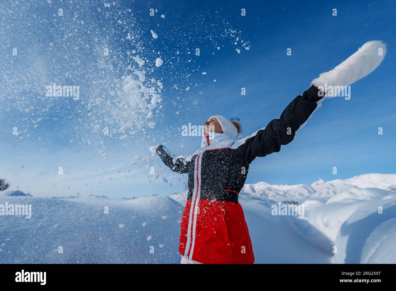 Young happy woman throw snow on winter mountains background Stock Photo