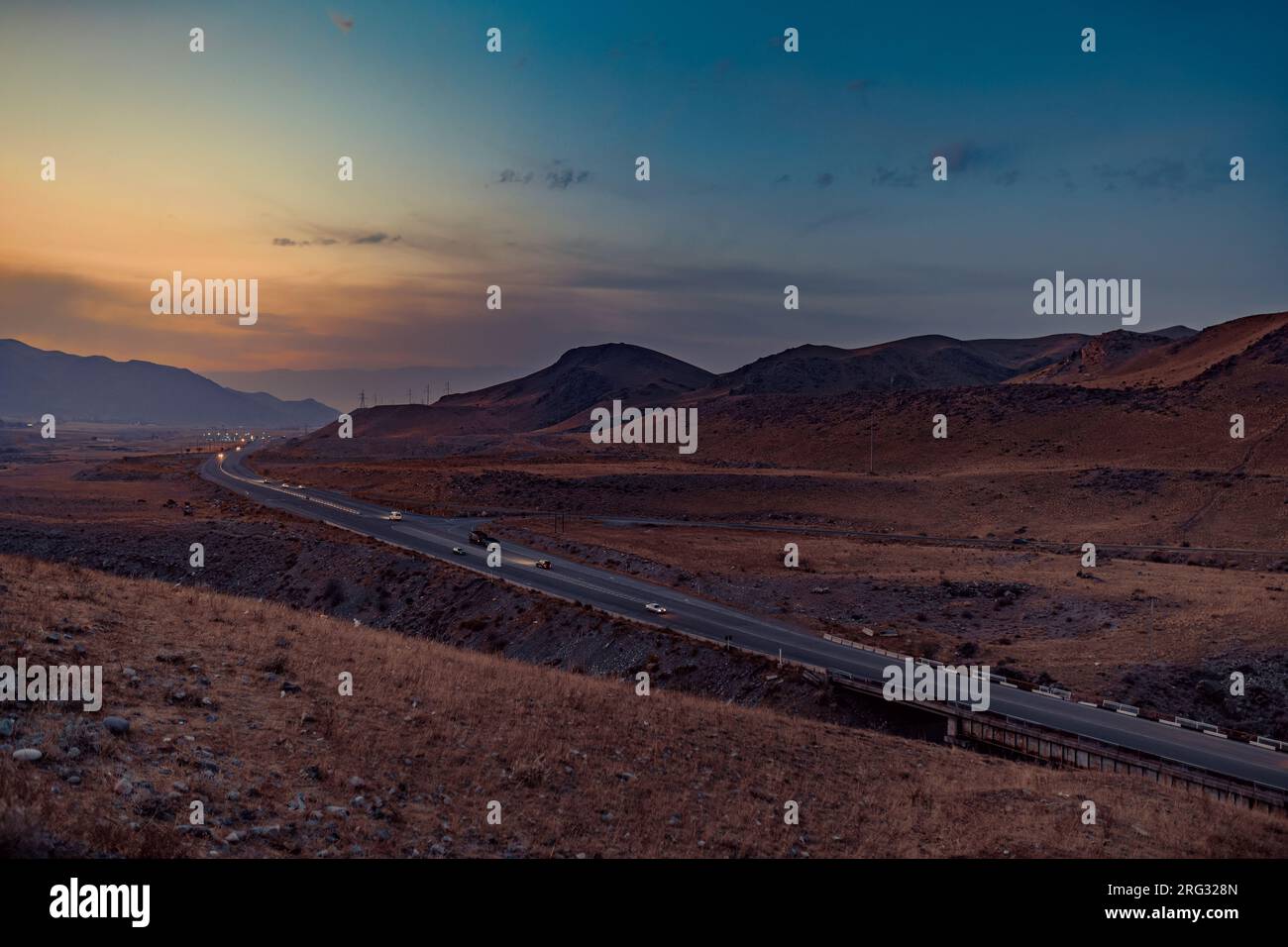 Cars on mountains road at sunset, Kyrgyzstan Stock Photo