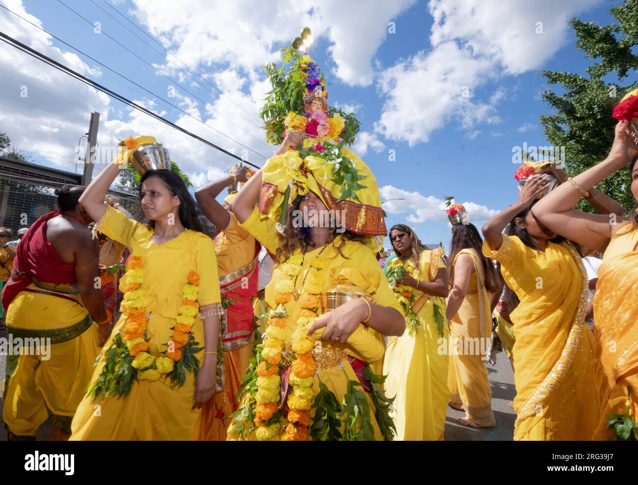 A pandita priestess marches from her temple to the site of the Thimithi fire walking ritual with an Karagam headdress. In Richmond Hill, Queens Stock Photo