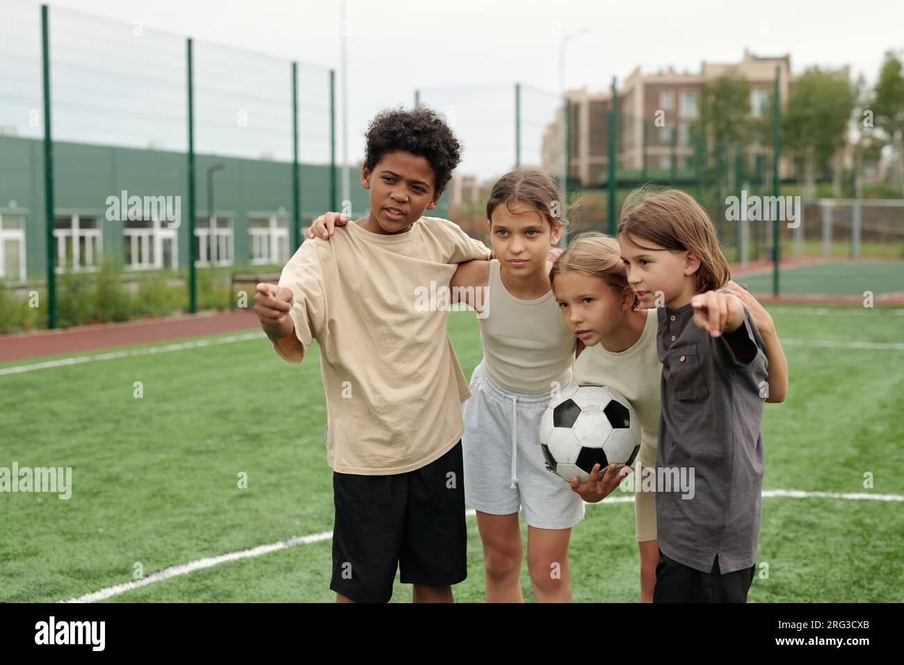 Cute African American schoolboy pointing forwards and explaining his ...