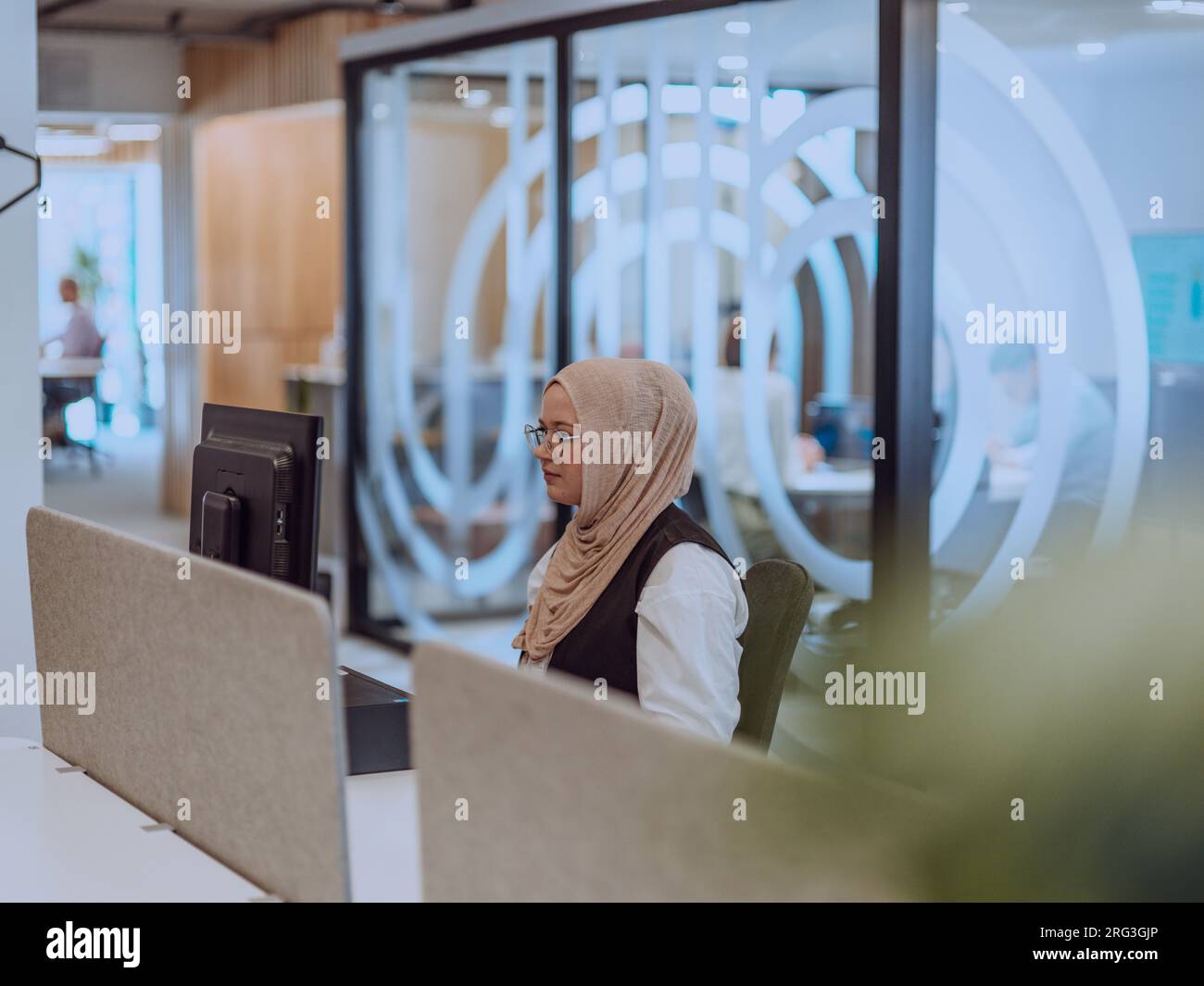 In a modern office, a young Muslim entrepreneur wearing a hijab sits ...