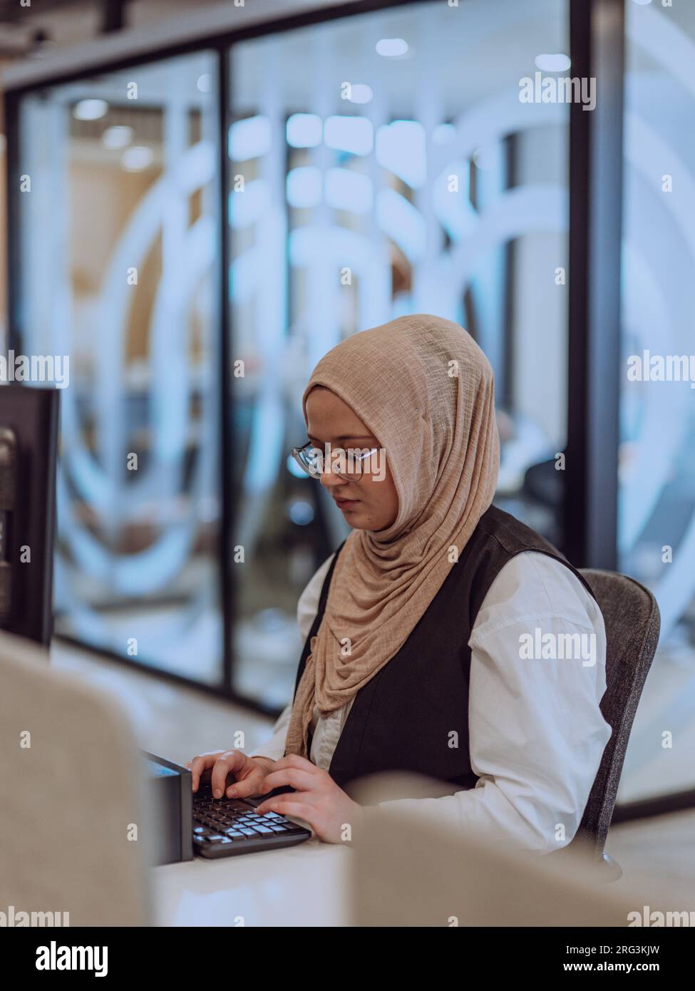 In a modern office, a young Muslim entrepreneur wearing a hijab sits ...