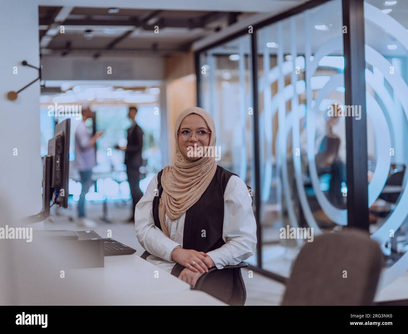 In a modern office, a young Muslim entrepreneur wearing a hijab sits ...