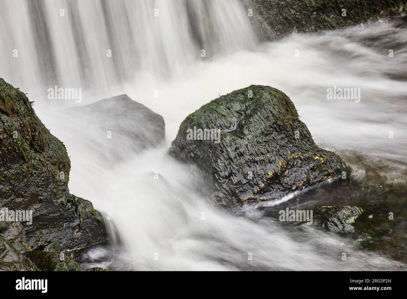 Water crashes onto rocks at the base of a vertical waterfall, on the coast at Speke's Mill Mouth, near Hartland Quay, Devon, Great Britain. Stock Photo