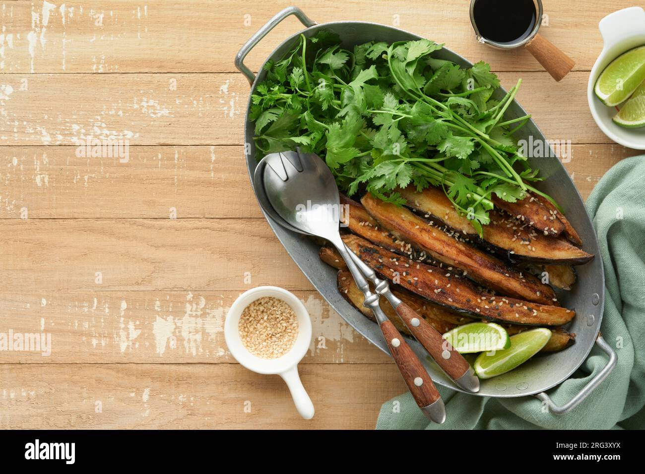 Grilled or baked eggplant slices in rice flour, with cilantro and soy sauce on old rustic wooden rustic table background. Top view with copy space. Stock Photo