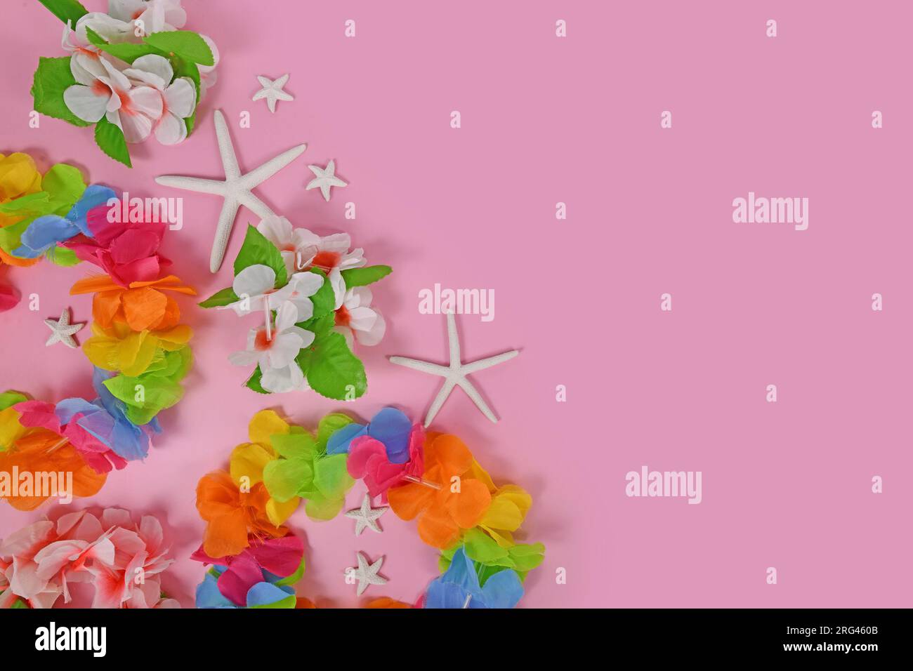 Bright flower lei necklaces on side of pink background with copy space