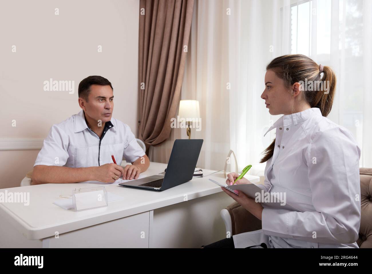 Two doctors man and woman talking, looking at computer screen Stock Photo