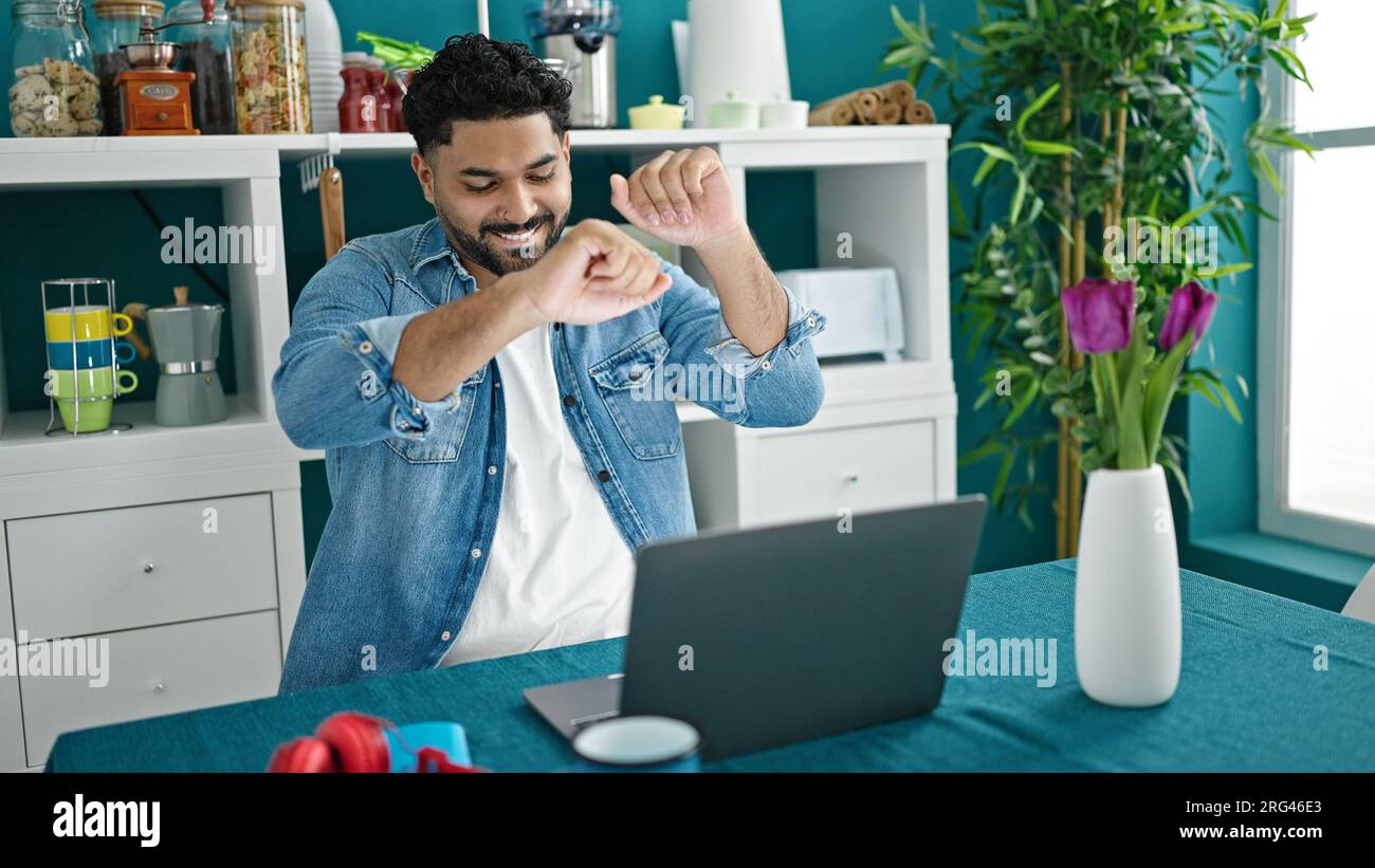African american man using laptop sitting on table dancing at dinning room Stock Photo